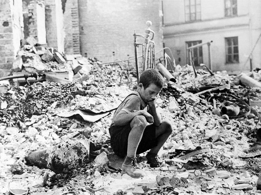 Zu Beginn des Zweiten Weltkriegs sitzt ein polnischer Junge trauernd in den Ruinen einer Straße in Warschau, Polen, September 1939