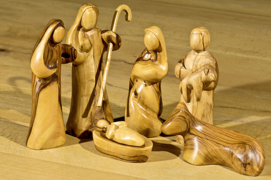Moderne Holzfiguren stellen die Heilige Familie dar. Mit Hirten und Ochse.